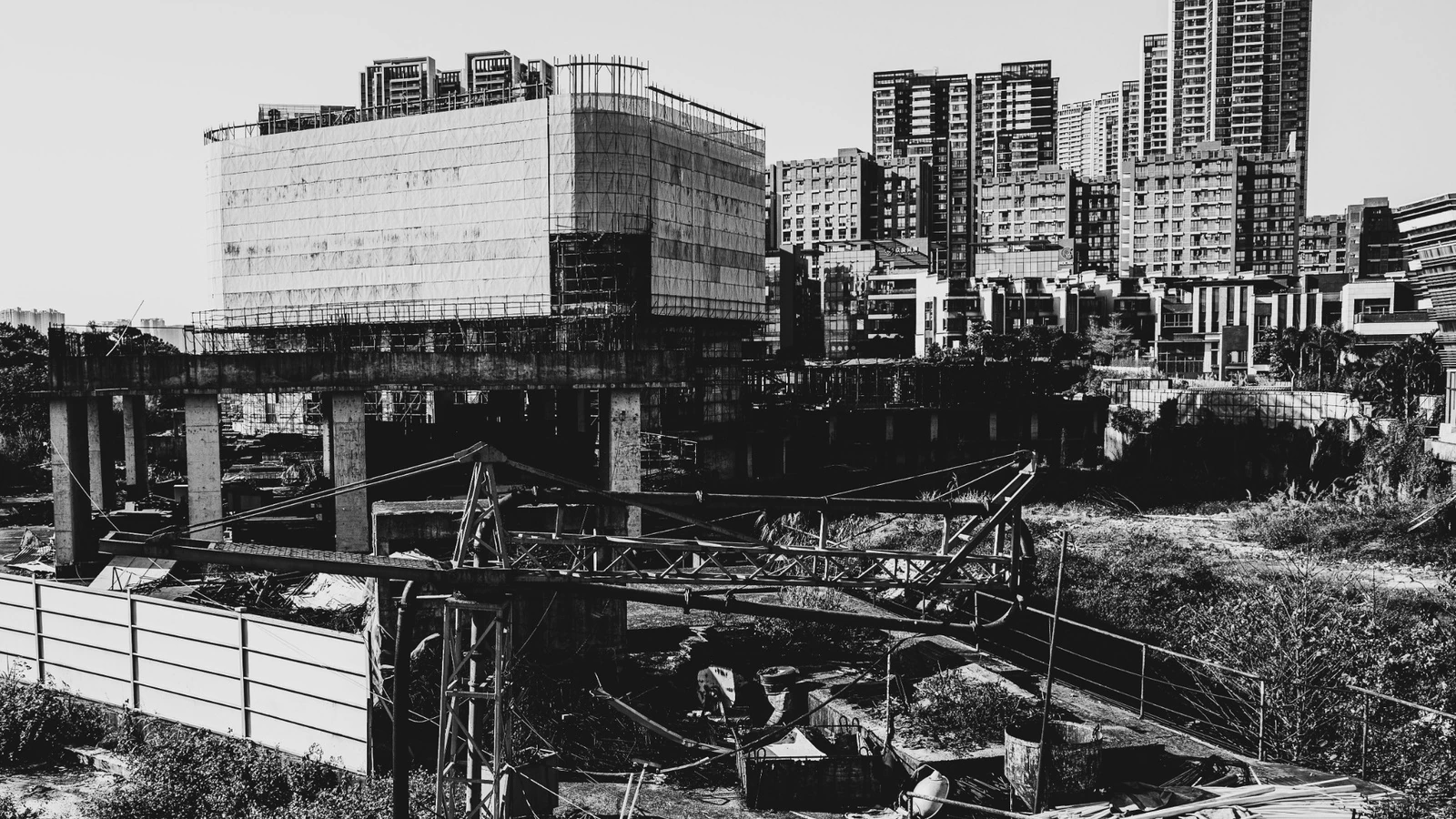 Obras de construcción en primer plano con edificios residenciales al fondo.